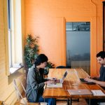 Two individuals working on laptops at a table, discussing the key components of an effective RFP management process.